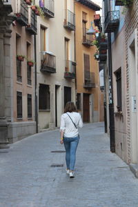 Rear view of woman walking on street amidst buildings