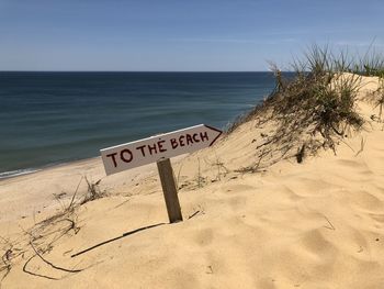 Text on beach against sky