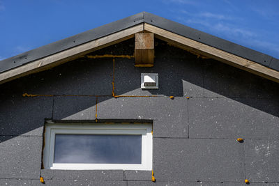 A plastic ventilation grille on the facade of the building made of black insulating polystyrene,