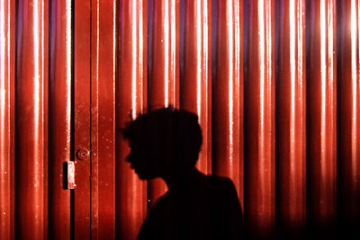 Portrait of silhouette woman standing against red wall