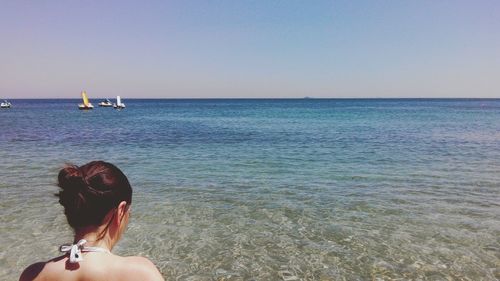 Rear view of man on beach against clear sky