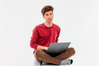 Full length of young man using phone against white background