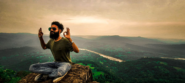 Full length of man photographing on landscape against mountain range