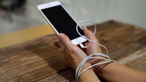 Low section of man using mobile phone on table