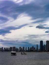 Sea by buildings against sky in city