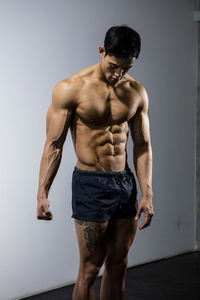 Shirtless muscular man standing against wall