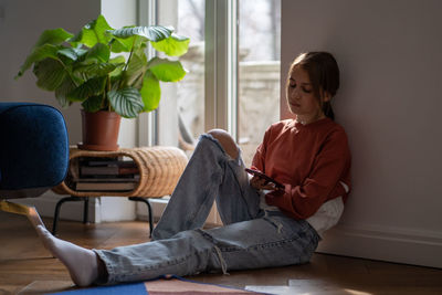 Side view of woman sitting on sofa at home