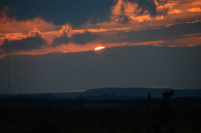 Scenic view of silhouette field against sky at sunset