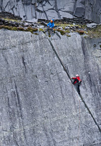 Woman climbing up steep rock face at slate quarry in north wales