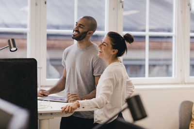 Happy professionals looking away while standing at office desk