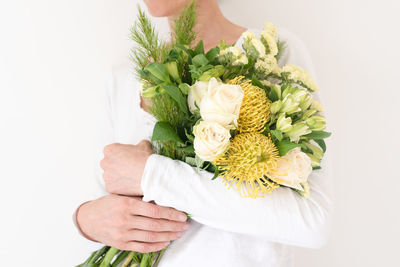 Midsection of woman holding bouquet against white background