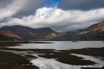 Scenic view of lake by mountains against sky