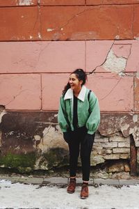 Young woman standing against brick wall