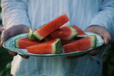 Midsection of man holding watermelons in plate