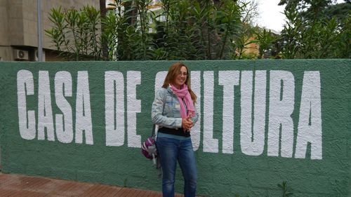 Woman looking away while standing against text on wall