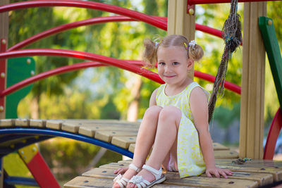 Portrait of smiling cute girl sitting at playground