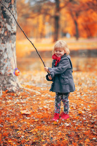 Girl playing with toy while standing at park during autumn