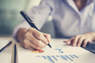 Midsection of man holding paper with text on table