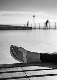 Low section of man on pier against sky