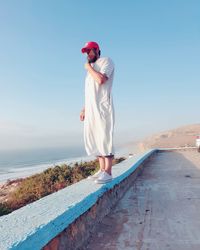 Woman standing on sea shore against clear sky