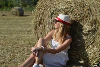 Young woman relaxing by hay bales on field