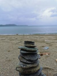 Stack of pebbles on beach against sky