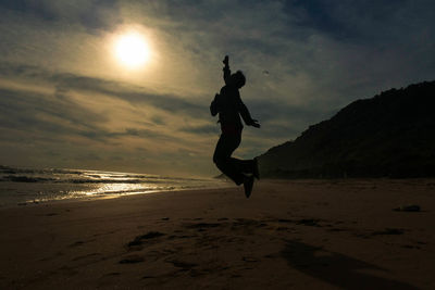 Silhouette of man on beach against sky during sunset