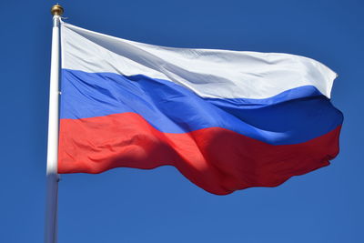 Low angle view of flag against blue sky