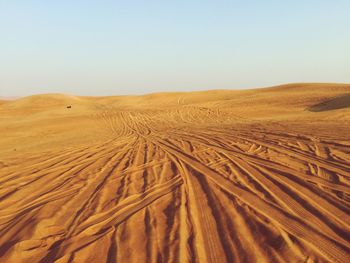 Tire tracks on desert against sky