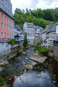 Bridge over river by buildings against sky