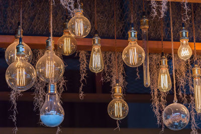 Close-up of illuminated light bulbs hanging from ceiling