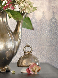 Flower vase on table against glass wall