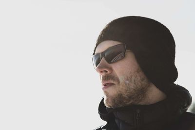 Portrait of young man wearing sunglasses against white background