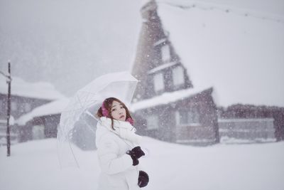 Woman with umbrella standing on field during winter