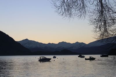 Silhouette boats in lake against sky during sunset