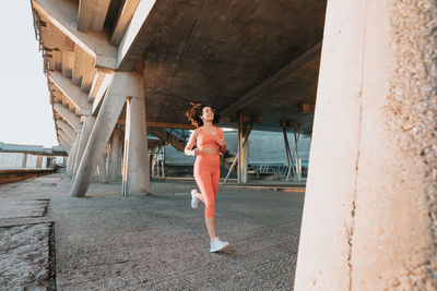 Full length of young woman standing on bridge