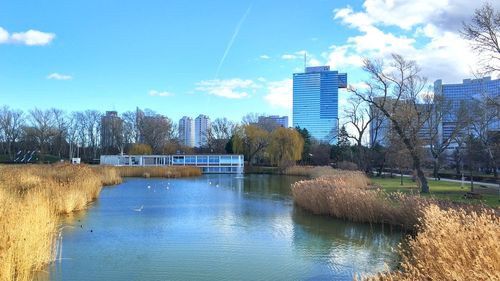 Buildings by river in city against sky