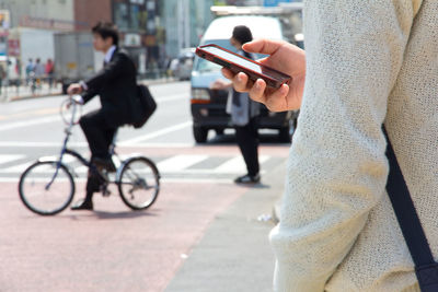 Midsection of man using mobile phone while standing on road