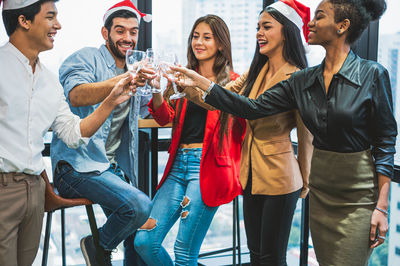 Cheerful friends toasting drinks during christmas