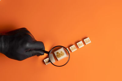 Close-up of hand holding smart phone against orange background