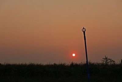 Street light on field against orange sky