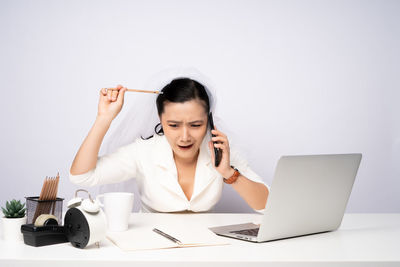 Mid adult man using mobile phone while sitting on table