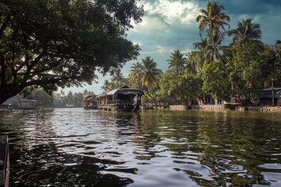 Scenic view of palm trees by canal against sky