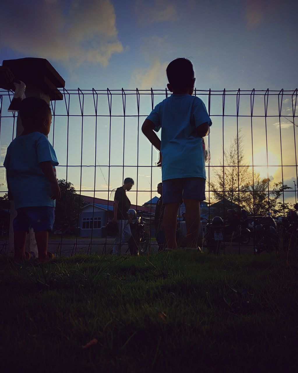 REAR VIEW OF BOY PLAYING ON FIELD AGAINST SKY