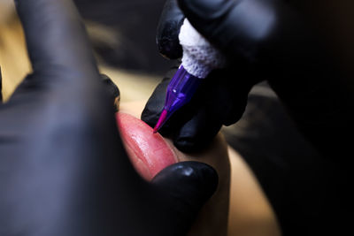 Tattoo artist stretched the lips of the model with two fingers and then performs a tattoo 