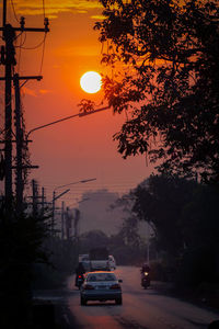 Cars on road against sky during sunset