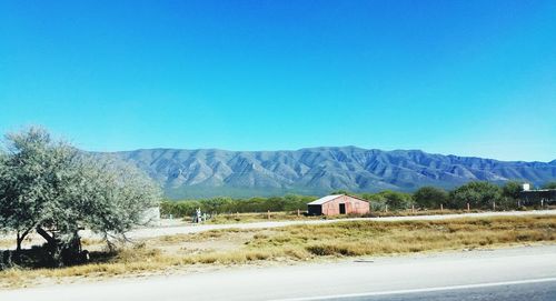 Houses by mountains against clear blue sky