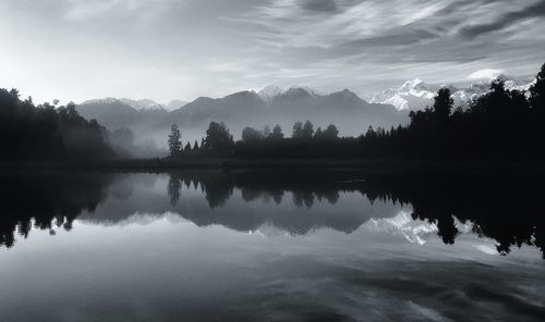 Scenic view of lake by silhouette trees against sky