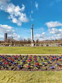 View of flowering plants in park against cloudy sky