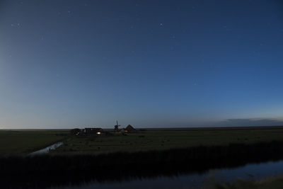 Scenic view of windmill on field against blue sky at night